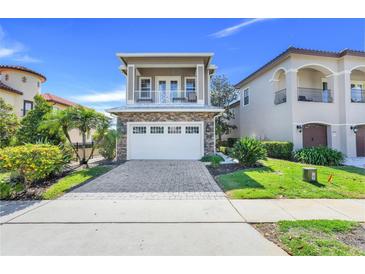 Charming two-story home with a stone facade, balcony, and paver driveway at 1021 Castle Pines Ct, Reunion, FL 34747