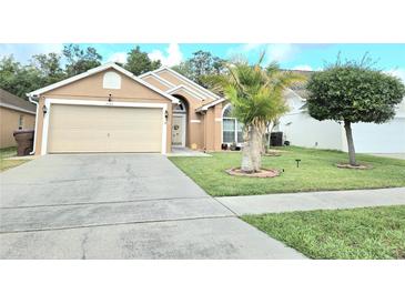Well-maintained home featuring a manicured lawn, a palm tree, and a two-car garage at 2346 Lily Pad Ln, Kissimmee, FL 34743