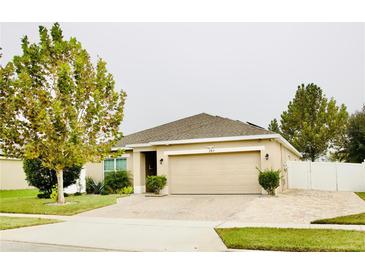 Charming single-story home with a manicured lawn, brick driveway and attached two-car garage at 247 Whispering Pines Way, Davenport, FL 33837