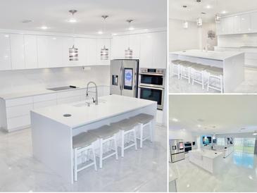 A sleek, modern kitchen features white cabinets, a spacious island with seating, and stainless steel appliances at 247 Whispering Pines Way, Davenport, FL 33837