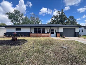 Charming single story home with a gray garage, white siding, front wood decorative fence and well-maintained lawn at 3045 Plaza Terrace Dr, Orlando, FL 32803