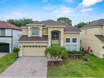 Inviting two-story home with a brick driveway, manicured lawn, and a two-car garage at 5321 Los Palma Vista Dr, Orlando, FL 32837