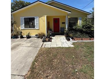 Charming yellow single-story home featuring a red front door, white shutters, and well-maintained landscaping at 716 Grove Ave, Orlando, FL 32805