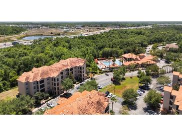 Expansive aerial view of the condo community with a pool, mature trees, and highway access at 1375 Tuscana Ln # 1207, Davenport, FL 33896