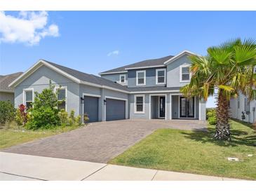 Charming two-story home featuring a three-car garage, brick driveway, and well-manicured lawn at 2110 Old Hollow Ln, Clermont, FL 34715