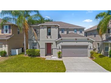 Two-story home with neutral paint, attached two-car garage and mature palm trees enhancing the front yard at 253 Aldridge Ln, Davenport, FL 33897