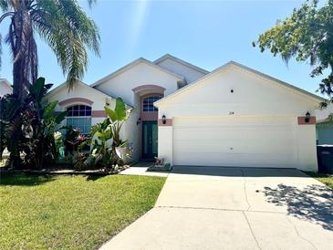 Charming single-Gathering home featuring a well-manicured lawn, inviting entrance, and attached two-car garage at 314 Saddle Ridge Dr, Davenport, FL 33896