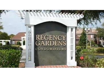Community sign for Regency Gardens Condominiums with lush landscaping and mature trees at 4301 Lizshire Ln # 306, Orlando, FL 32822