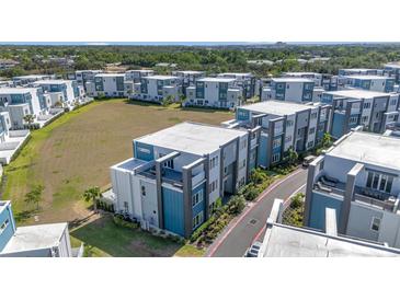An aerial view of modern townhouse-style condos with manicured landscaping and a well-kept lawn at 7740 Sandy Ridge Dr # 236, Reunion, FL 34747