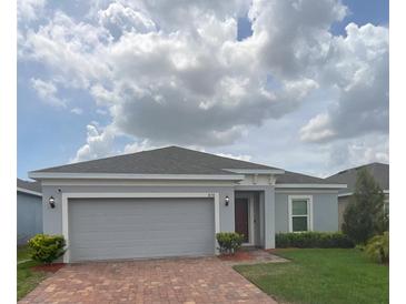 Charming single-story home with a well-manicured lawn and beautiful brick paved driveway at 878 Benjamin Trl, Davenport, FL 33837