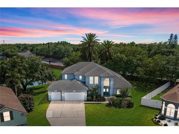 Stunning two-story home featuring a three-car garage, lush landscaping, and a beautiful dusk sky at 13044 Lakeshore Grove Dr, Winter Garden, FL 34787