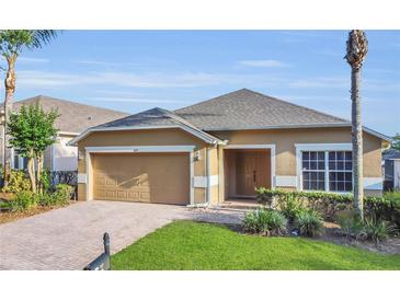Charming one-story home with a well-maintained lawn, brick driveway, and attached two-car garage at 147 Bridgewater Dr, Davenport, FL 33897