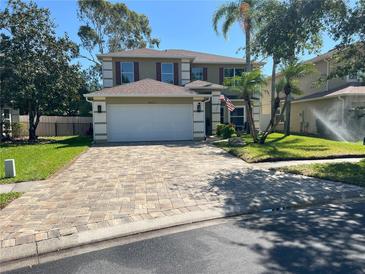 Charming two-story home featuring a paved driveway, a well-manicured lawn, and an attached two-car garage at 14963 Yorkshire Run Dr, Orlando, FL 32828