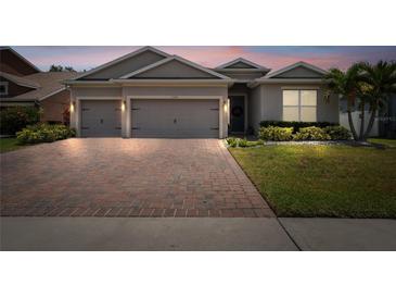 Charming single-story home featuring a brick driveway, a well-manicured lawn and a two-car garage at 1557 Alligator St, St Cloud, FL 34771