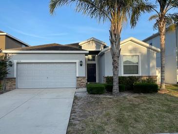 Charming single-story home featuring a gray facade, two-car garage, and well-maintained landscaping at 1574 Thetford Cir, Orlando, FL 32824