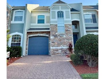 Two-story townhome featuring a brick driveway, attached garage, and stone facade at 15851 Woodland Spring Ct, Orlando, FL 32828