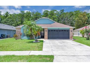 Charming single-story home with blue accents, a well-manicured lawn, and a two-car garage at 2398 Queenswood Cir, Kissimmee, FL 34743