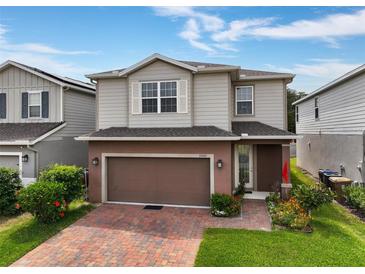 Two-story home with a brick paver driveway, two car garage, neutral siding, and manicured landscaping at 3084 Slough Creek Dr, Kissimmee, FL 34744