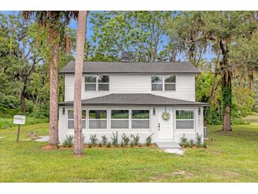 Charming two-story home with a white exterior, well-manicured lawn, and a welcoming front entrance at 5851 Se Drew Rd, Belleview, FL 34420