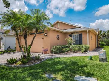 Charming home featuring lush landscaping, a well-manicured lawn, and a two-car garage at 112 Grand Canal Dr, Poinciana, FL 34759