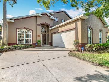 Charming stucco home featuring a two-car garage, well-manicured landscaping, and a welcoming front entrance at 207 Bailey Cir, Davenport, FL 33897