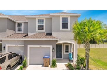 Charming two-story townhome featuring a one-car garage, gray exterior paint, and tropical landscaping at 3617 Anibal St, Kissimmee, FL 34746