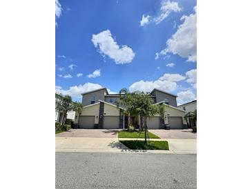 Attractive townhomes featuring modern architecture, well-maintained landscaping, and brick paved driveways at 703 Ocean Course Ave, Davenport, FL 33896