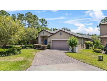 Inviting single-story home featuring a well-manicured lawn and a brick driveway at 1103 Cypress Pointe Blvd, Davenport, FL 33896