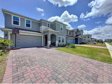 Two-story home with a brick paver driveway, landscaping and a two-car garage at 1181 Lone Palm Way, St Cloud, FL 34771