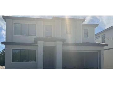 Two-story home with large windows and open two-car garage, showcasing modern design at 1270 Butterfly, Davenport, FL 33837