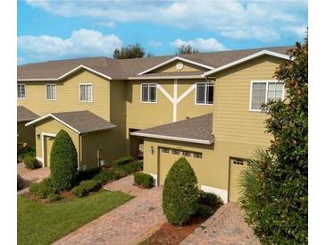 Inviting townhomes feature attached garages, manicured lawns, and neutral-toned exteriors under a blue sky at 1849 Chatham Place Dr, Orlando, FL 32824