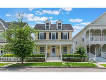 Charming two-story yellow home with a welcoming front porch and white picket fence at 206 Norfolk Pl, Celebration, FL 34747