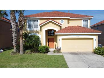 Charming two-story home featuring a red tile roof, lush landscaping, and an attached two car garage at 219 Rosso Dr, Davenport, FL 33837