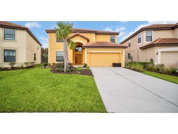 Inviting two-story home with a well-manicured lawn, palm tree, and a two-car garage and red tile roof at 2630 Tranquility Way, Kissimmee, FL 34746
