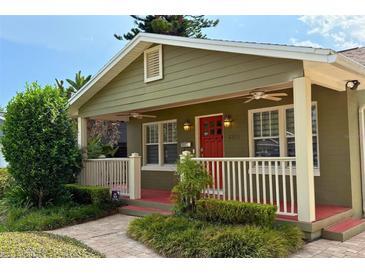 Charming bungalow featuring a cozy front porch with a red door and meticulously landscaped yard at 2810 Elizabeth Ave, Orlando, FL 32804