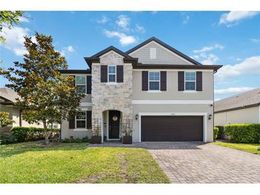 Beautiful two-story home featuring a stone facade, lush lawn and attached two car garage at 3425 Middlebrook Pl, Harmony, FL 34773