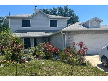 Charming two-story home with an attached garage and a welcoming front yard filled with plants at 172 Pinewood Cir, Kissimmee, FL 34743