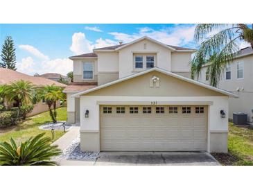 A two-story home boasts a two-car garage, a well-manicured lawn, and stylish exterior lighting at 521 Rena Dr, Davenport, FL 33897