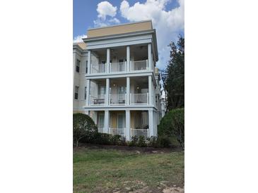 Three story condo building with white balconies and trim over a yellow base near mature landscaping at 7509 Mourning Dove Cir # 303, Reunion, FL 34747