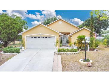 Charming single-story home with a well-manicured lawn, two-car garage, and inviting entryway at 906 Elm Forest Dr, Minneola, FL 34715