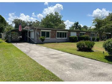 Charming single-story brick home with a covered parking area and well-maintained front lawn at 930 Aultman Rd, Kissimmee, FL 34744