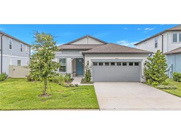 Charming single-story home featuring a well-manicured lawn, light gray siding, and a two-car garage at 983 Silverlake Blvd, Lake Alfred, FL 33850