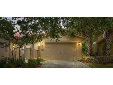 A single-Gathering home featuring an attached two-car garage and a stone-paved driveway, with lovely trees providing shade at 2376 Palm Tree Dr, Kissimmee, FL 34759