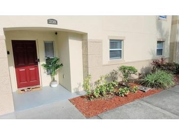 Charming townhouse entrance with red door and freshly landscaped garden at 2729 Club Cortile Cir, Kissimmee, FL 34746