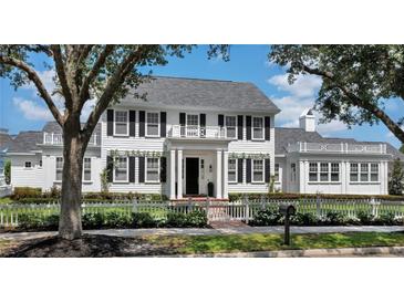 Charming two-story home features a white picket fence, black shutters, and a well-manicured lawn at 423 Arbor Cir, Celebration, FL 34747