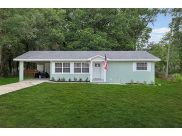 Charming one-story home featuring a well-manicured lawn and covered parking at 918 Louise Ln, Deland, FL 32720