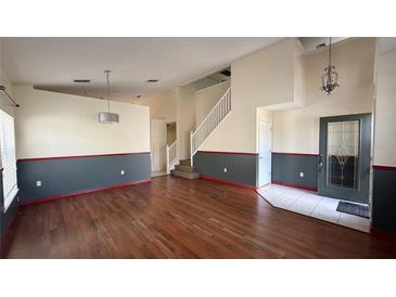Bright living room boasts hardwood floors and staircase, enhanced with two-tone walls and a contemporary light fixture at 979 Hacienda Cir, Kissimmee, FL 34741