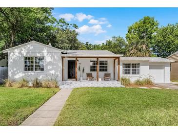 Charming single-story home with a covered porch, patterned patio, and beautiful landscaping at 1012 N Shine Ave, Orlando, FL 32803