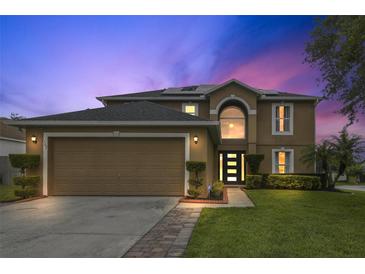 Charming two-story home with a well-manicured lawn and two car garage at dusk at 102 Royalty Cir, Sanford, FL 32771