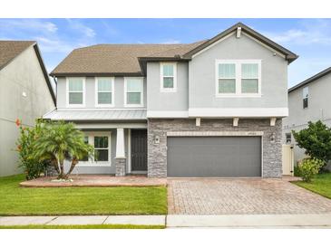 Charming two-story home featuring a stone facade, gray paint, and well-manicured landscaping at 14160 Dove Hollow Dr, Orlando, FL 32824